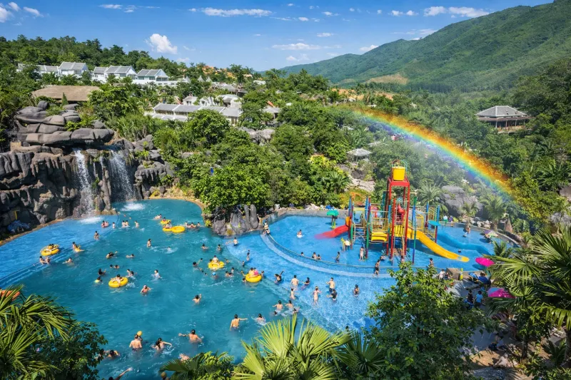 Than Tai Hot Springs water park near Da Nang with rainbow arching over swimming pools and slides